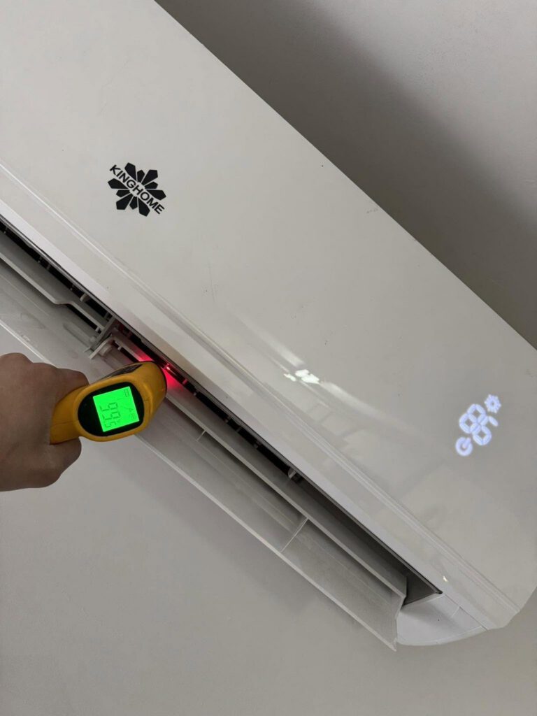 Technician checking a ductless mini-split's air temperature with an infrared thermometer